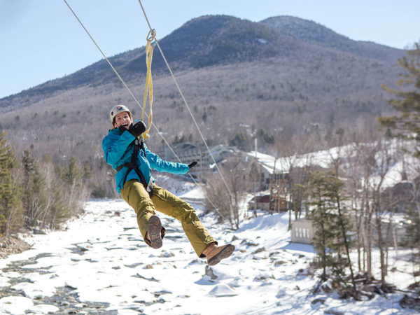 Woman ziplining into the snowy White Mountains in Lincoln, NH