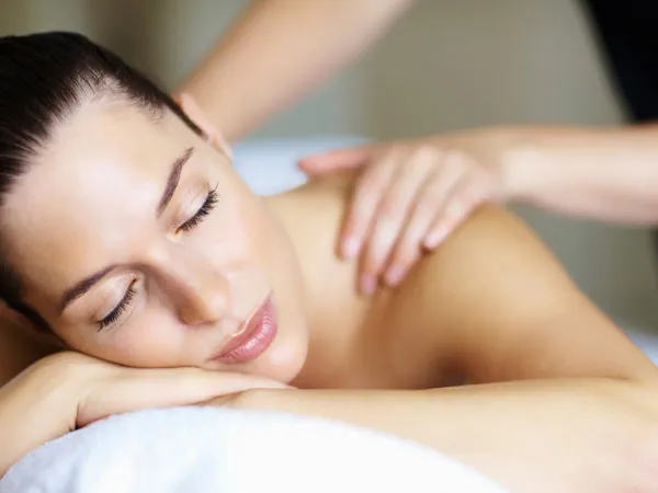 Woman lying on a massage table getting a massage wearing a white towel